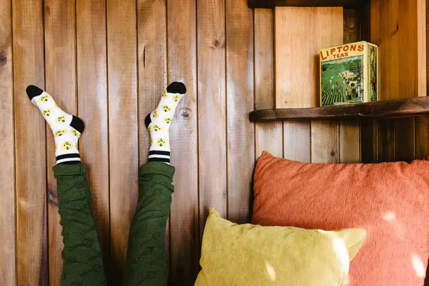 Feet in socks resting up against a wooden wall